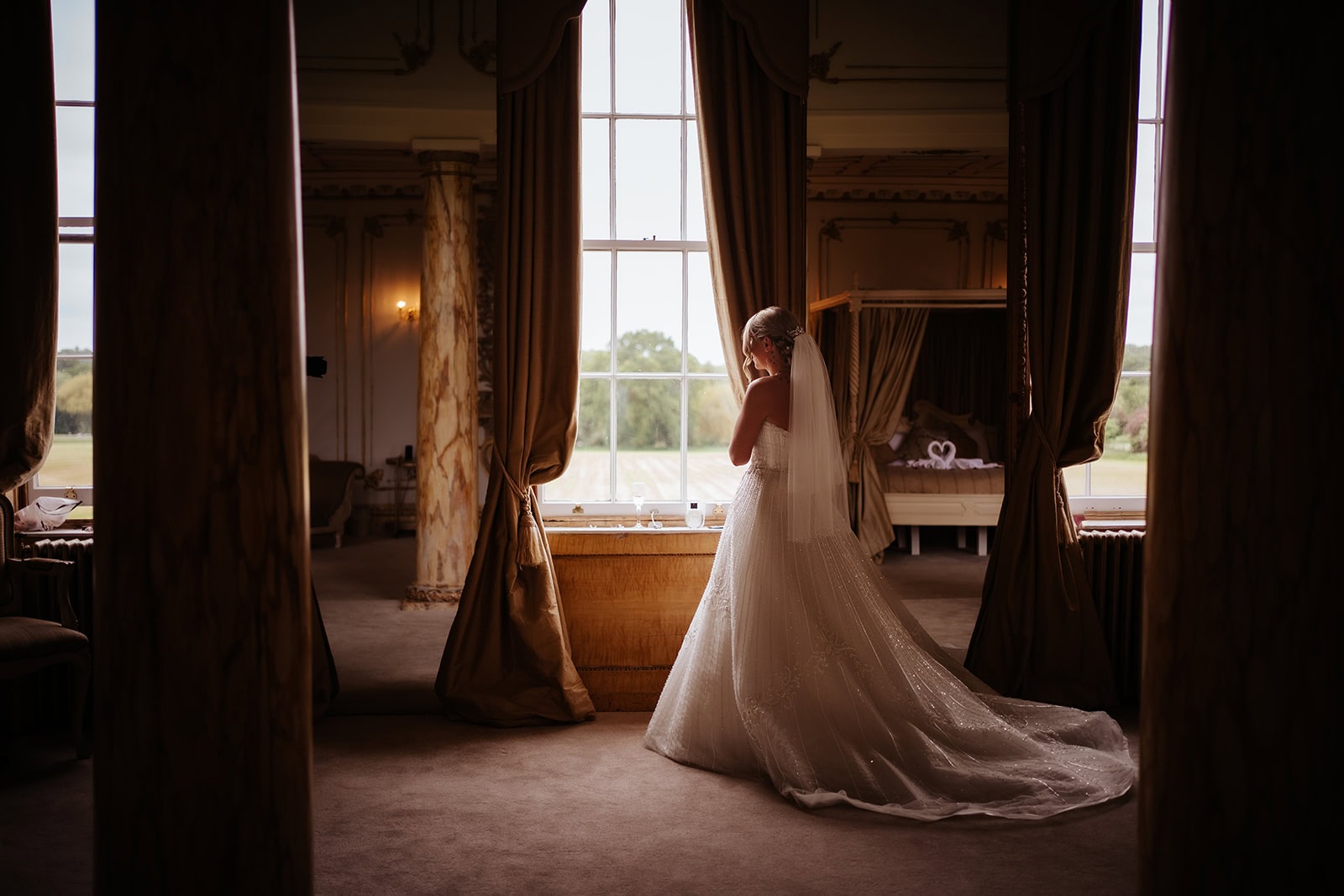 Bride looking out of the Rococo bridal suite at Gosfield Hall wedding venue in Essex – bridal morning photography by Tel, Lily & White