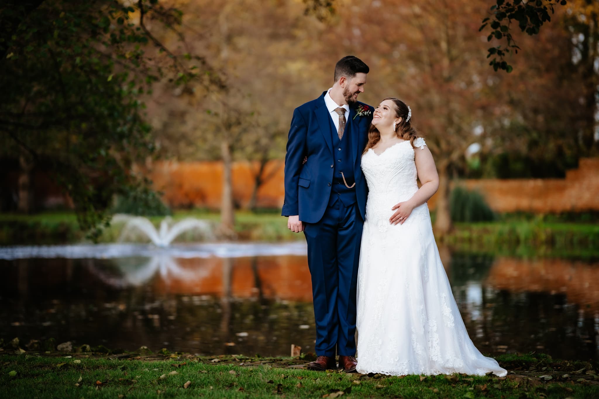 A quiet, unscripted moment between Amy and Rob by the lake at Leez Priory. The soft winter light catches the ripples of the fountain behind them as they share a private laugh, documented with a cinematic, storytelling perspective.
