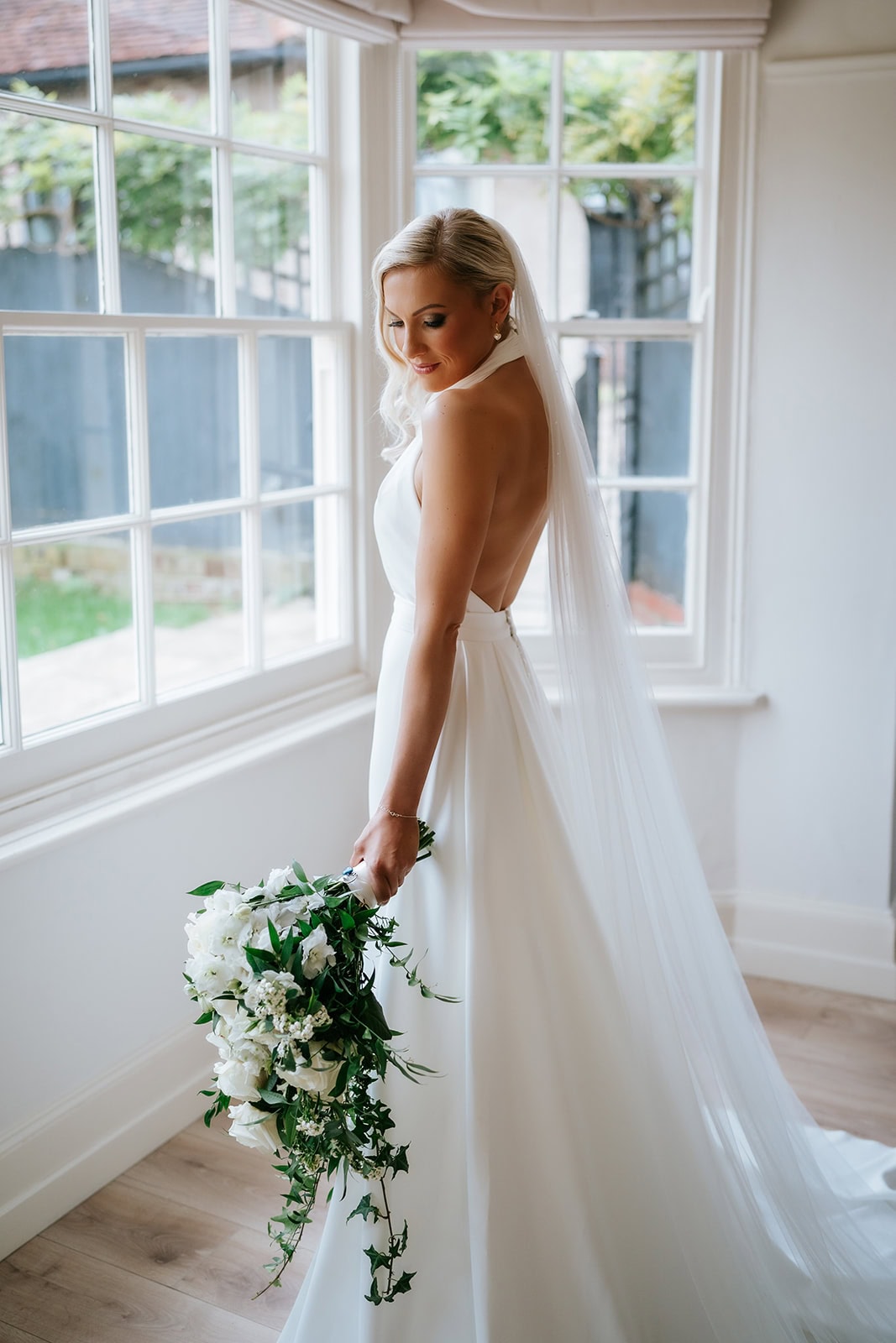 Editorial wedding photography in Essex showing an elegant bride at a window in a luxury venue.