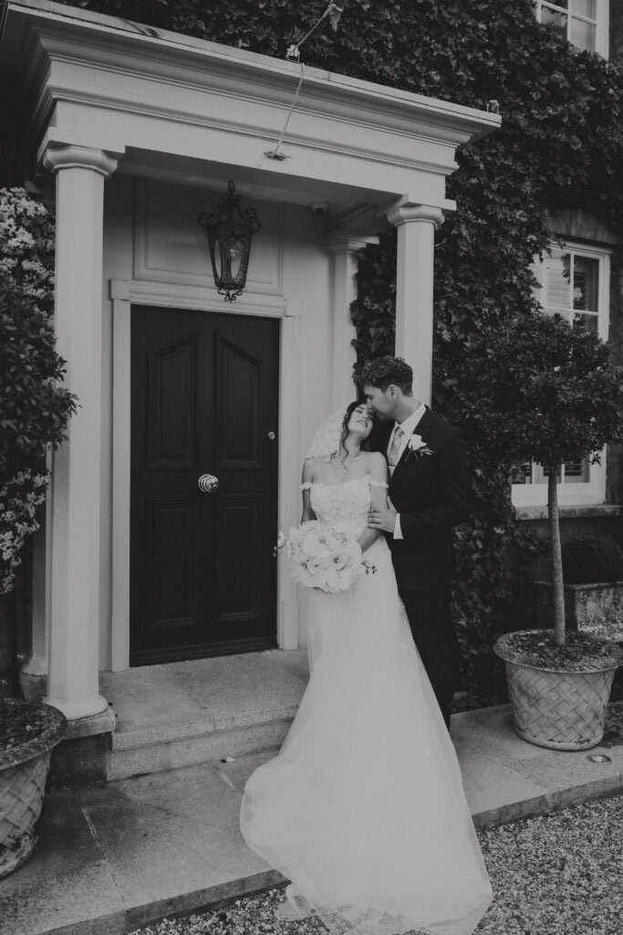 Editorial Essex wedding photography; a romantic bride and groom portrait in front of a luxury manor house entrance.