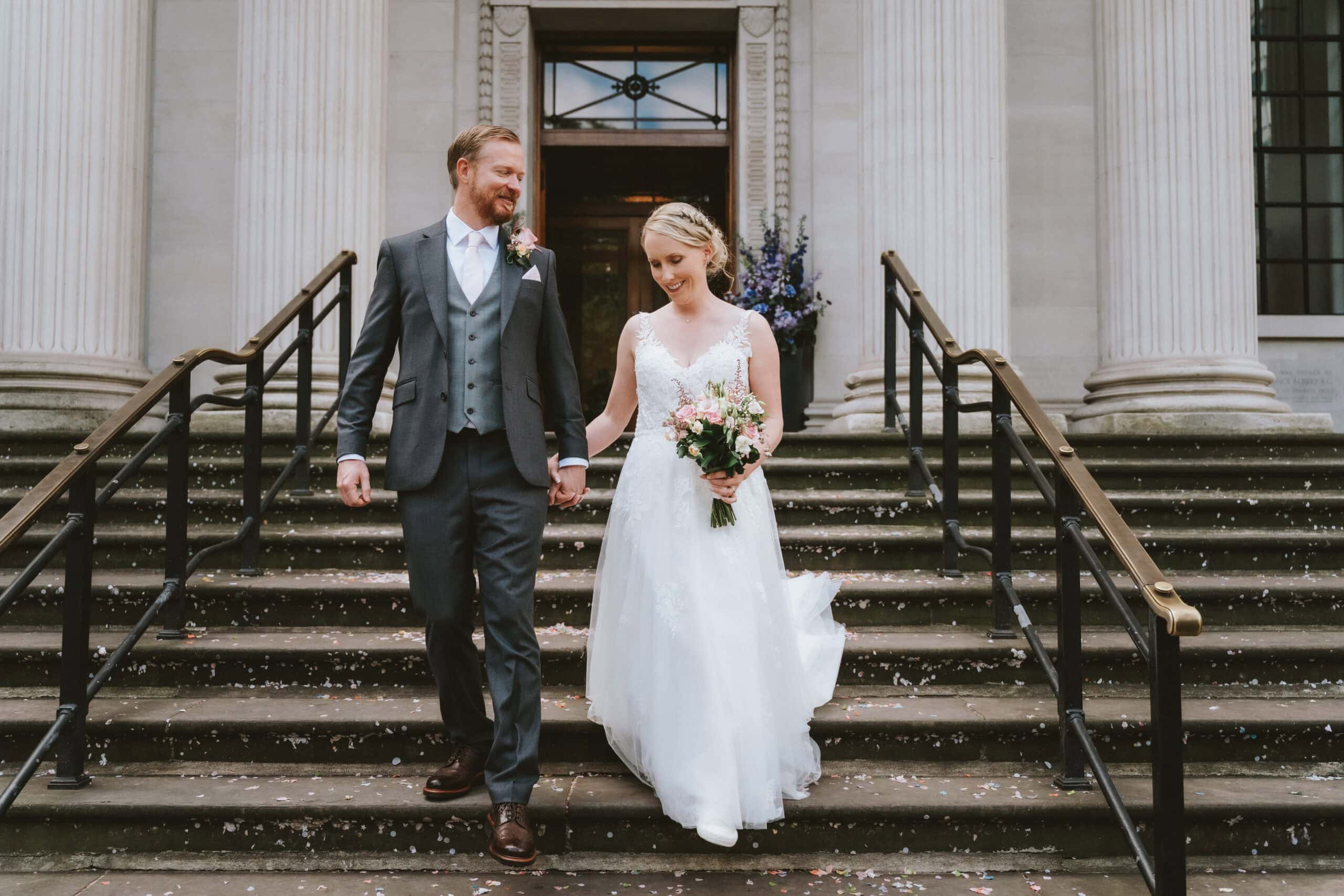 Editorial wedding photography at Old Marylebone Town Hall London featuring a bride and groom walking down the iconic stone steps during a city elopement.