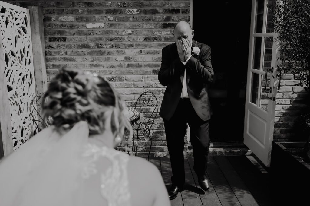 Father of the bride on the balcony at Friern Manor bridal suite – emotional documentary moment captured by Lily & White
