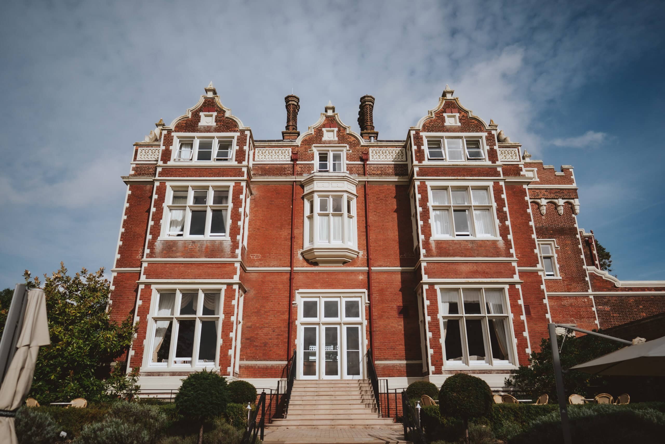The Georgian redbrick facade of Wivenhoe House hotel and wedding venue in Colchester with distinctive Dutch gables and formal gardens — photographed by Lily & White
