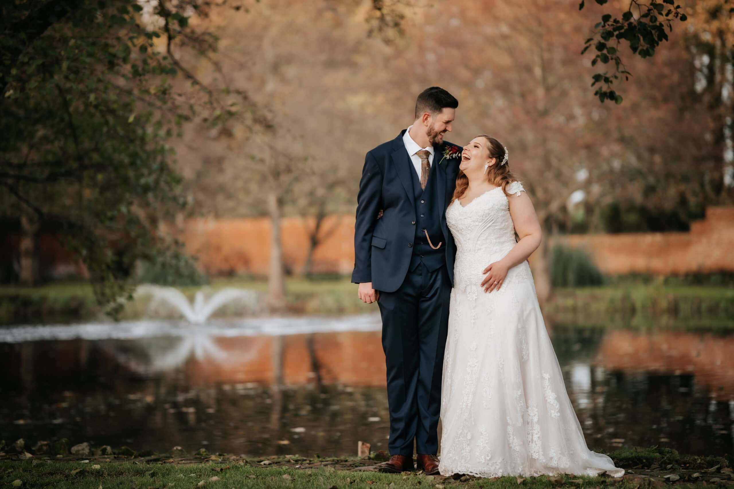 A quiet, unscripted moment between Amy and Rob by the lake at Leez Priory. The soft winter light catches the ripples of the fountain behind them as they share a private laugh, documented with a cinematic, storytelling perspective.