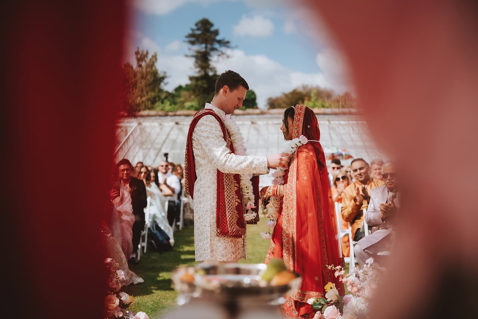Editorial wedding photography at Braxted Park in Essex, capturing a bride in a traditional red lehenga and a groom in an ivory sherwani for a beautiful fusion wedding ceremony.