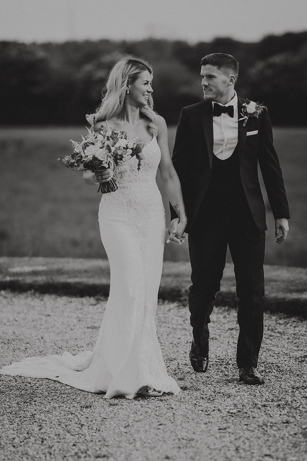 Bride and groom walking together in the parkland at Gosfield Hall wedding venue in Essex — timeless black and white wedding photography by Lily & White