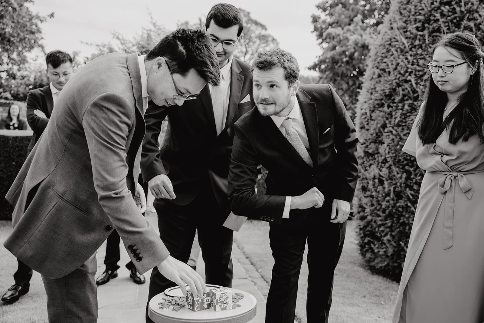 Jeffrey and groomsmen completing a challenge during the Chinese door games in the grounds of Blake Hall, July 2024 – wedding photography by Tel, Lily & White