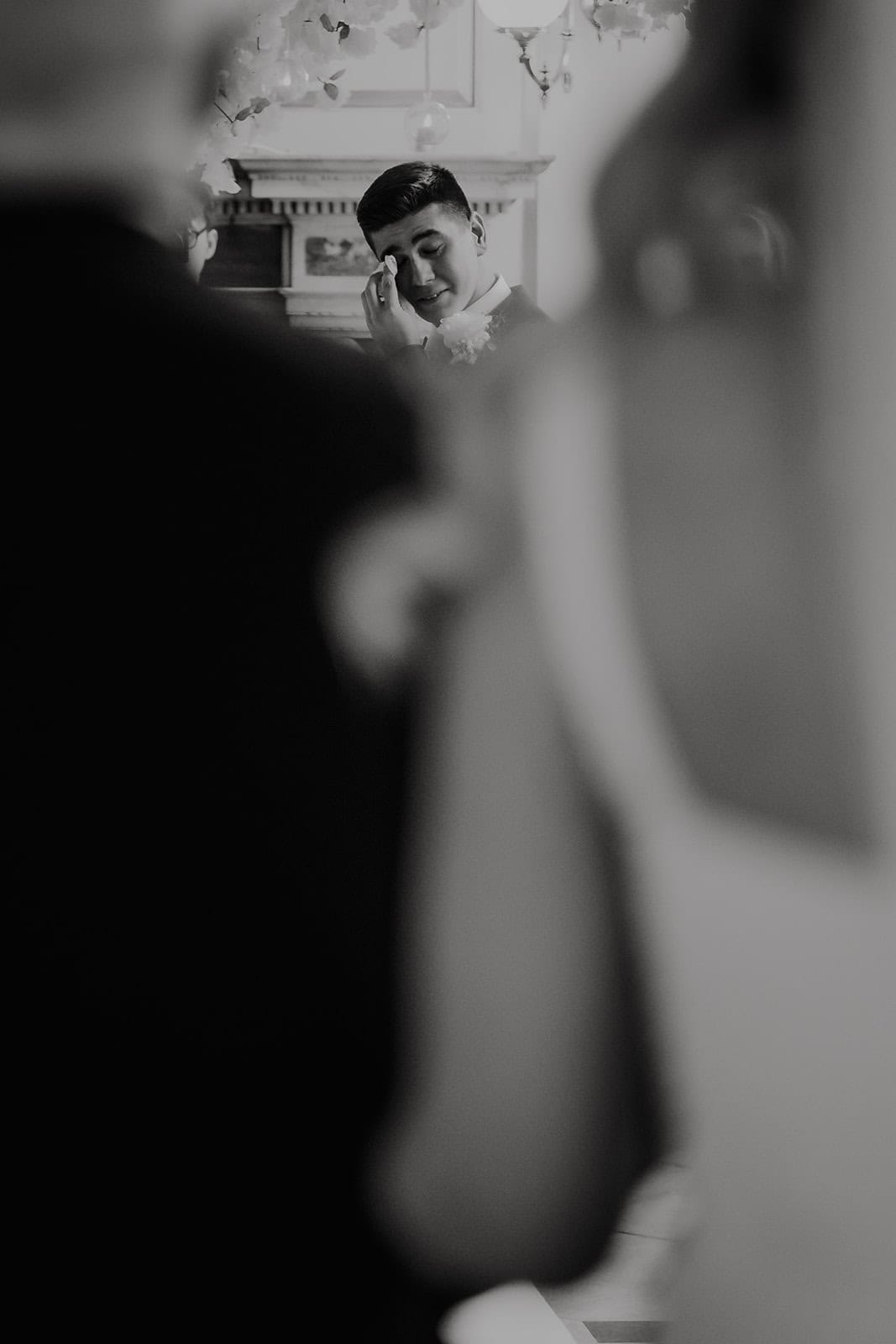 Emotional candid wedding photography in Essex capturing a groom wiping a tear during the ceremony.