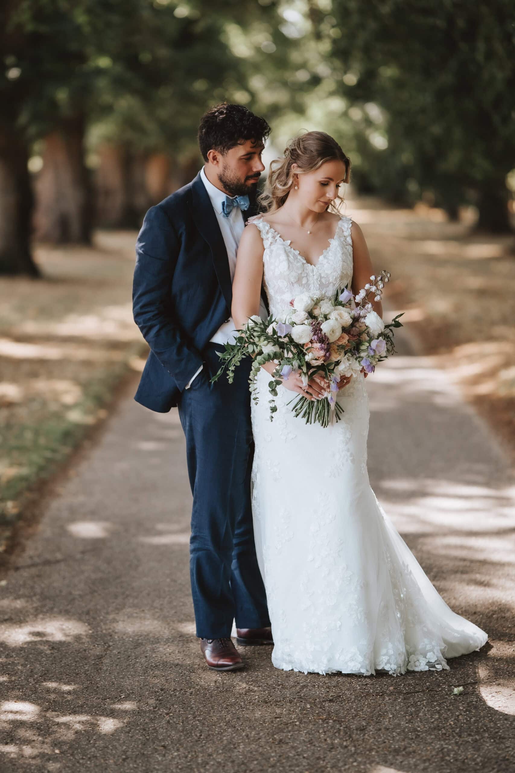 Editorial wedding photography in Essex showing couple in intimate moment on tree-lined path with natural autumn light and romantic bokeh